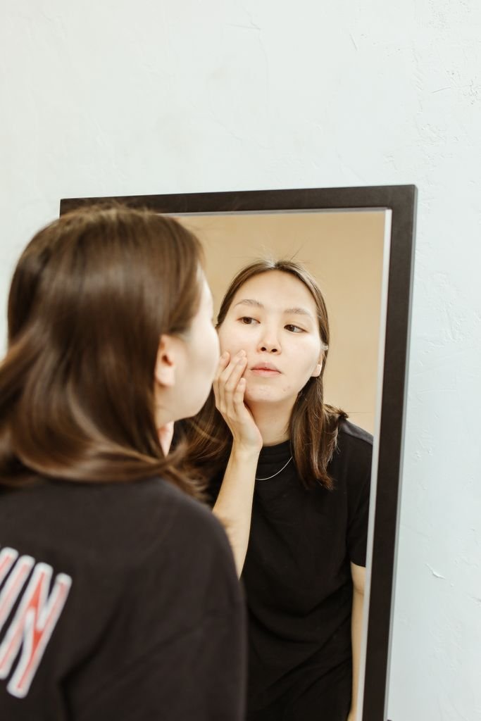 Woman checking a breakout in the mirror while learning how to get rid of pimples overnight