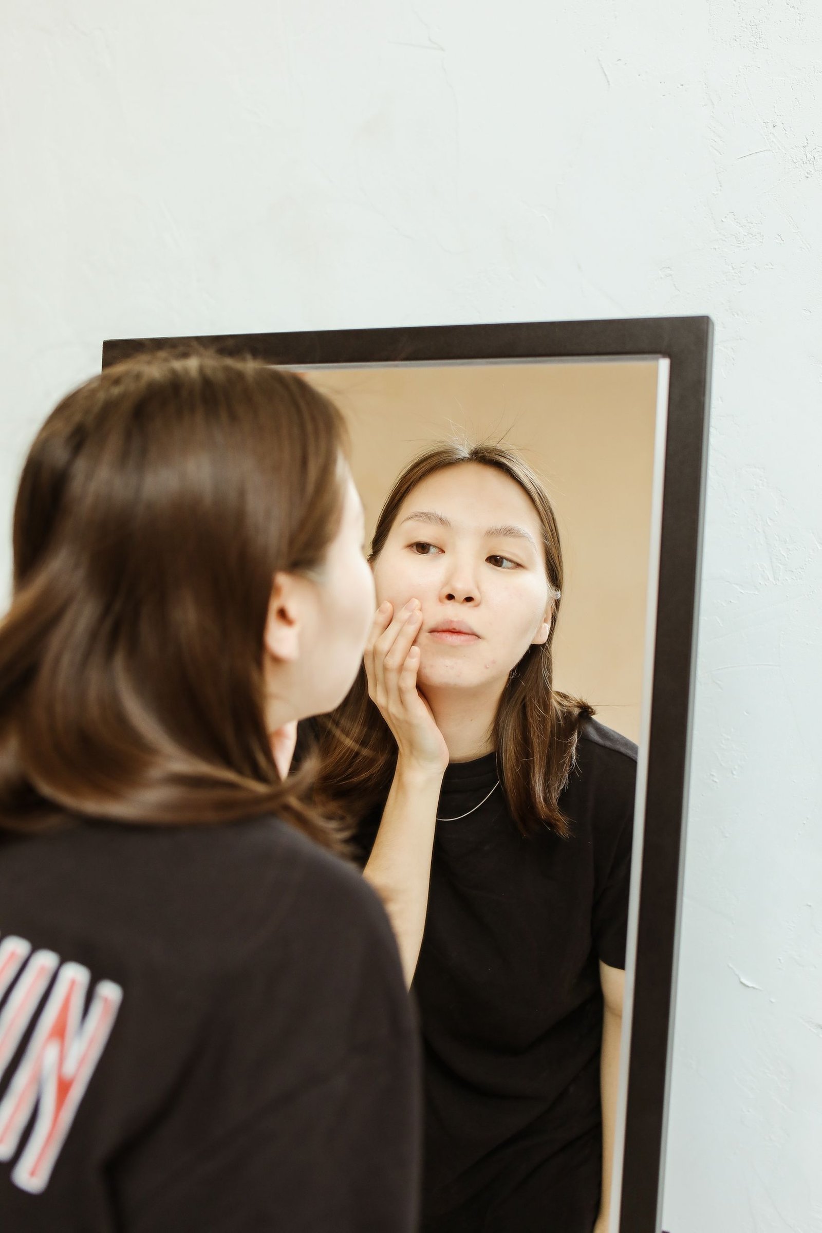 Woman checking a breakout in the mirror while learning how to get rid of pimples overnight